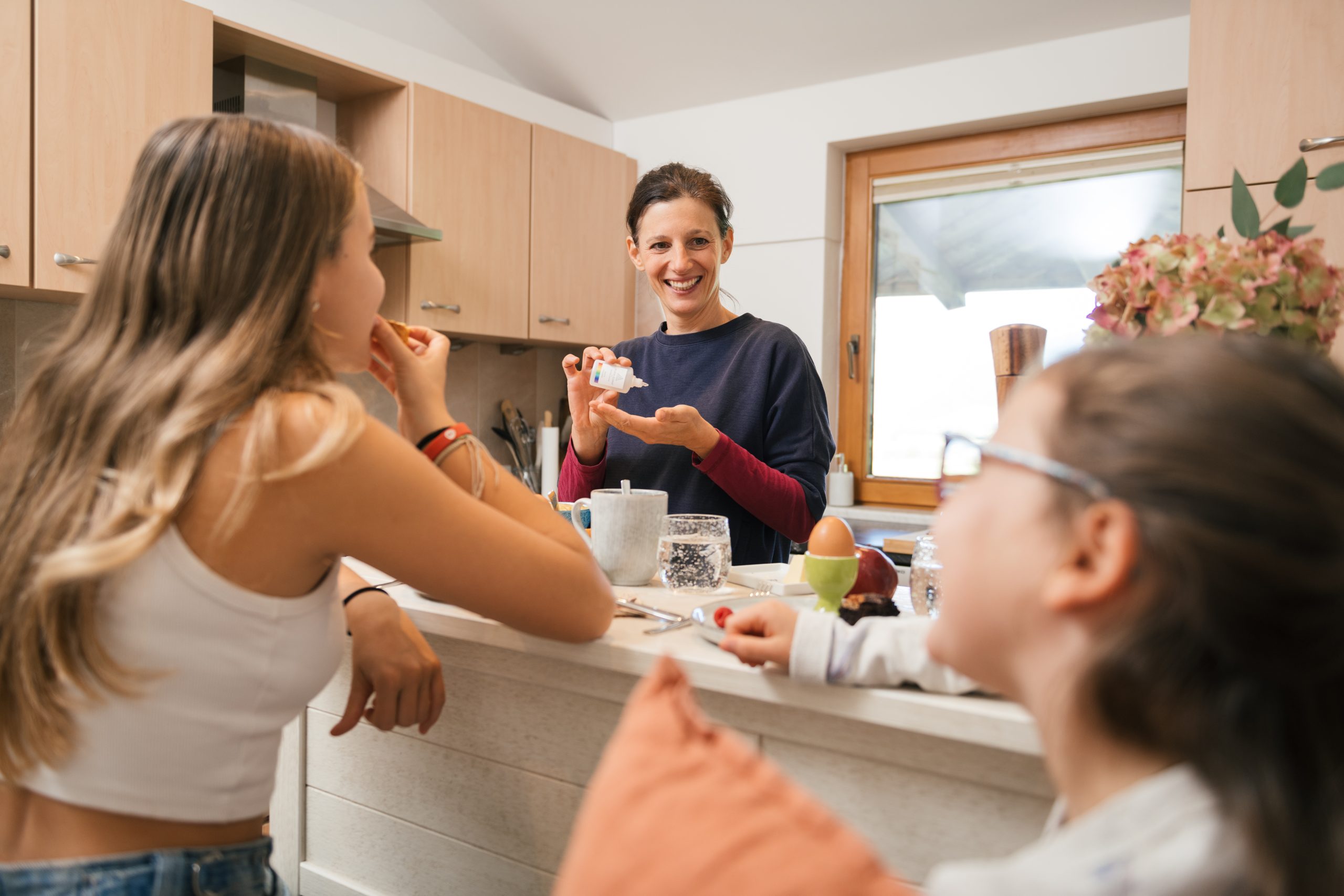 Familie in der Küche, lächelnd über einen Moment der Energiearbeit beim Frühstück.