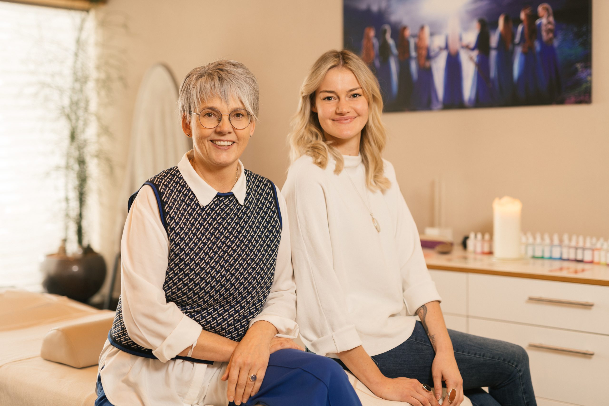 Zwei Frauen sitzen in einem Raum f&uuml;r Energiearbeit mit entspannter Atmosph&auml;re und Kerzenlicht.