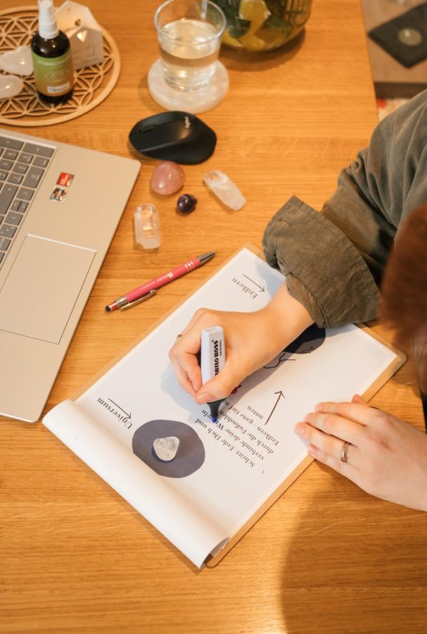 Person arbeitet an Energiearbeit, umgeben von Laptop und Kristallen auf einem Schreibtisch.