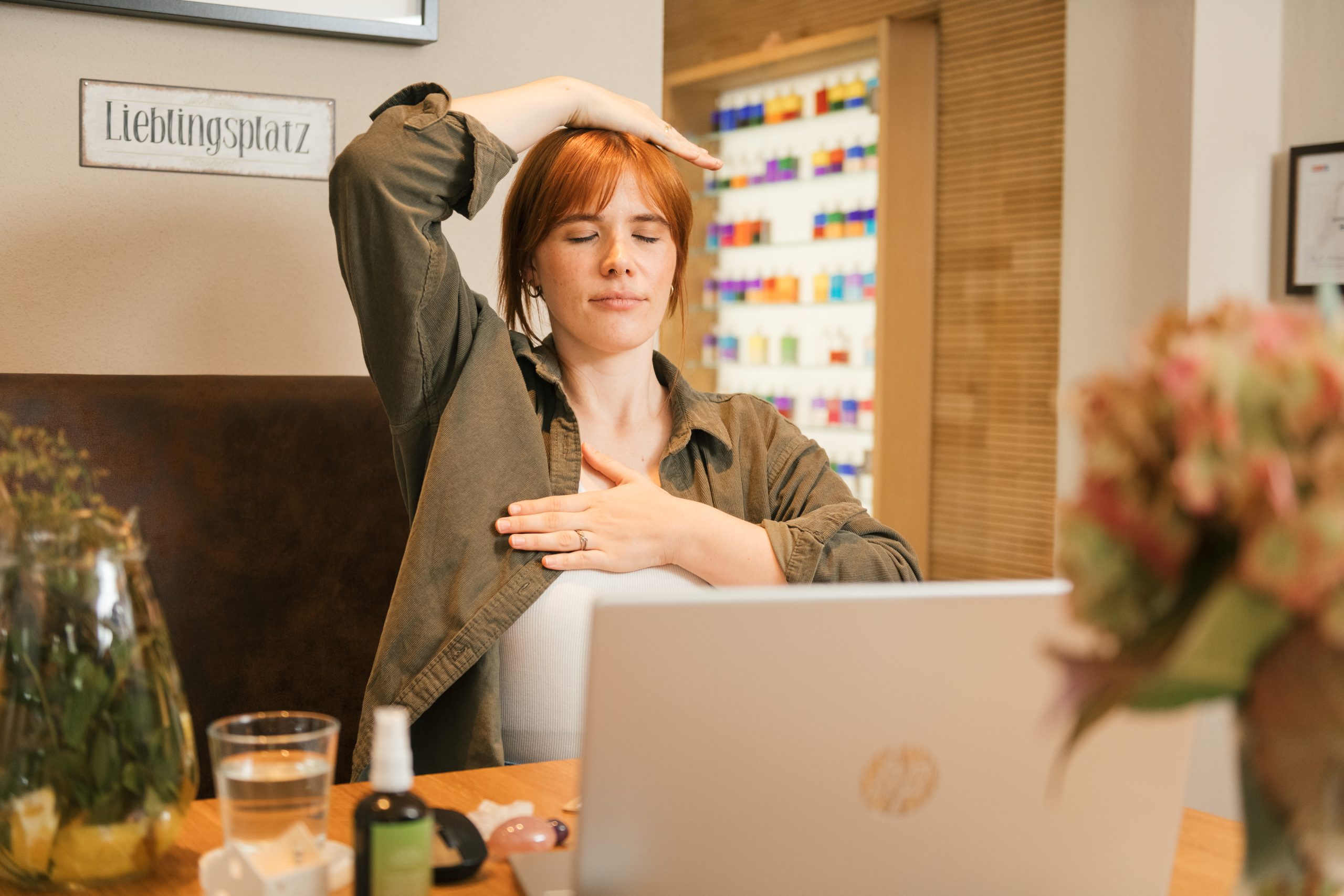 Plattform-67475 Frau bei der Energiearbeit am Computer, entspannt mit geschlossenen Augen, umgeben von Kristallen und Pflanzen.