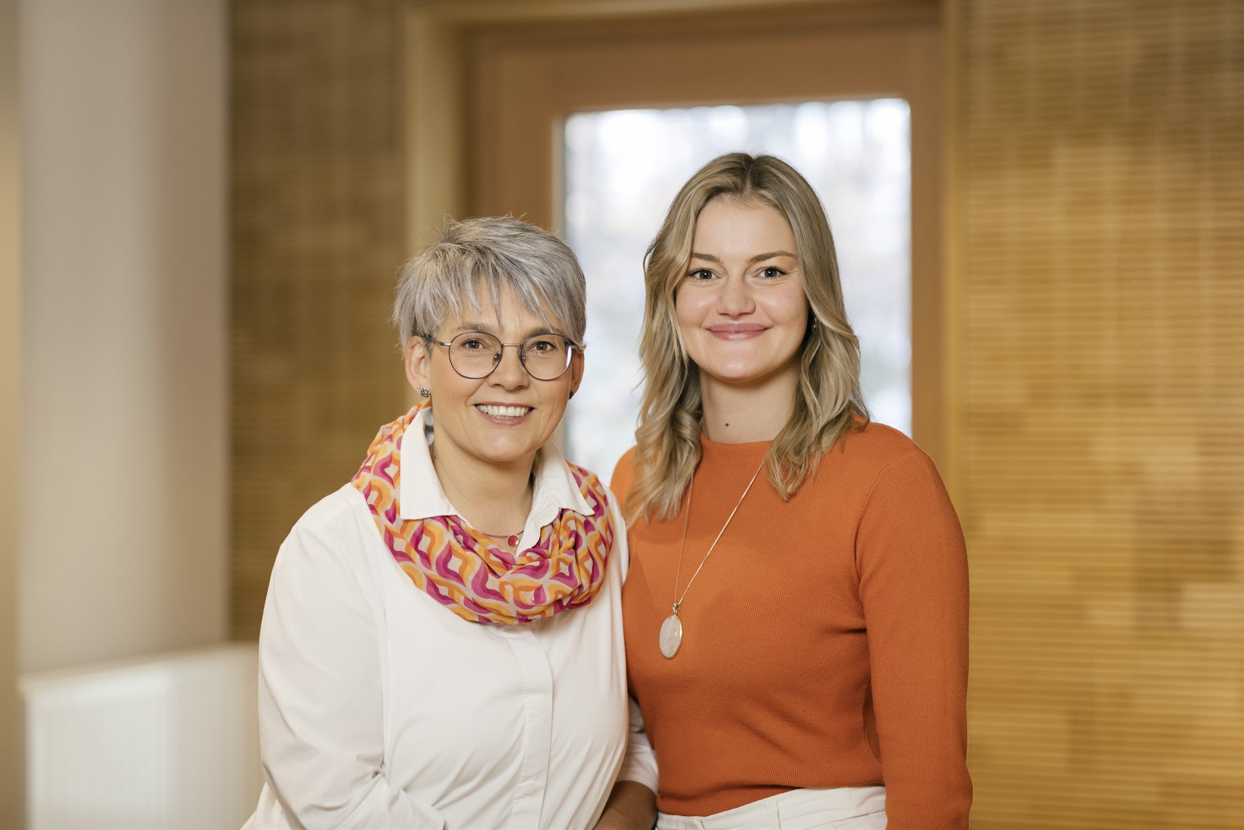 Zwei Frauen lächeln in die Kamera, Symbol für Energiearbeit und positive Energie.