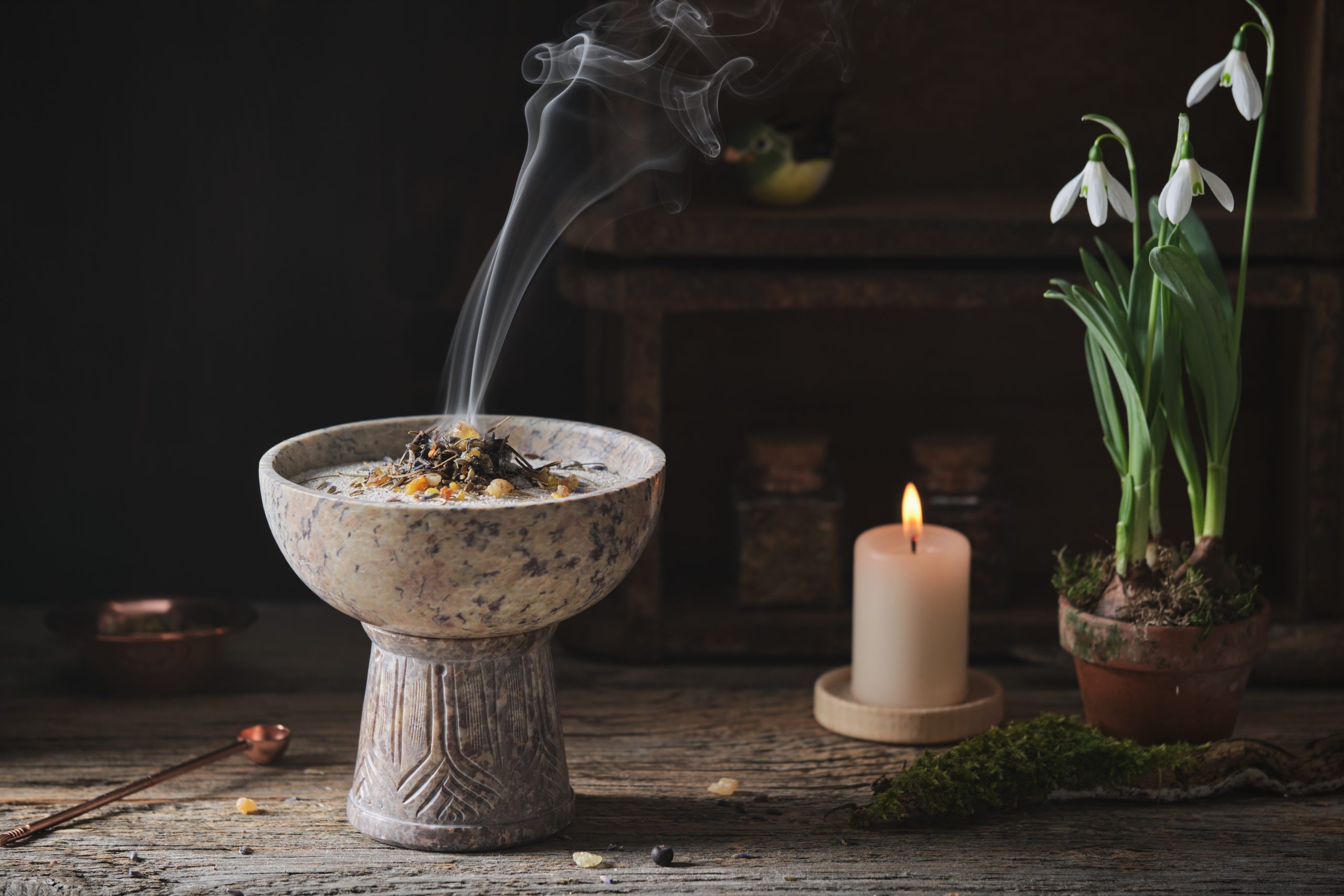 Räuchergefäß mit Rauch, Kerze und Schneeglöckchen für beruhigende Energiearbeit und spirituelle Atmosphäre.