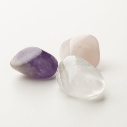 Polierte Heilsteine für Energiearbeit: Amethyst, Rosenquarz und Bergkristall auf weißem Hintergrund.