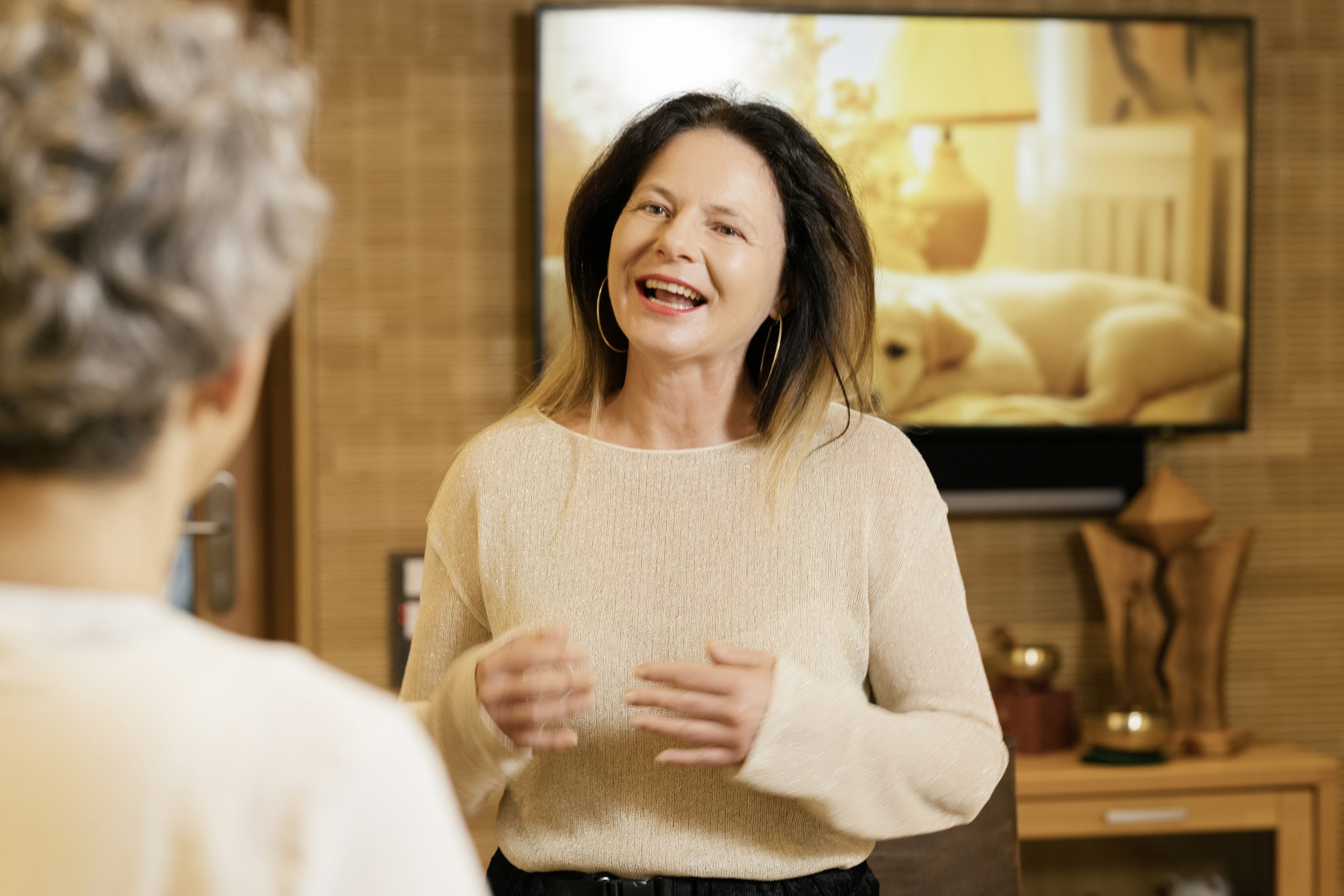 Frau erklärt Energiearbeit in einem Wohnzimmer mit Hundebild im Hintergrund.