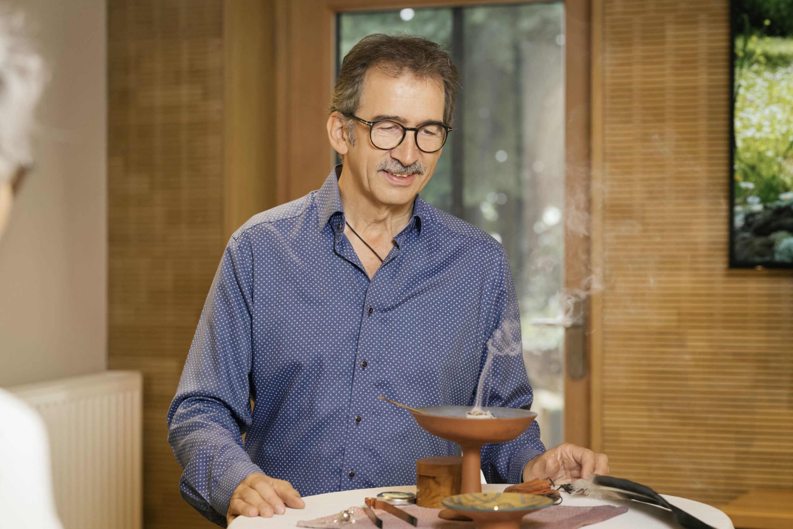 Ein Mann bei der Energiearbeit mit Räucherwerk, umgeben von natürlichen Materialien in einem harmonischen Raum.